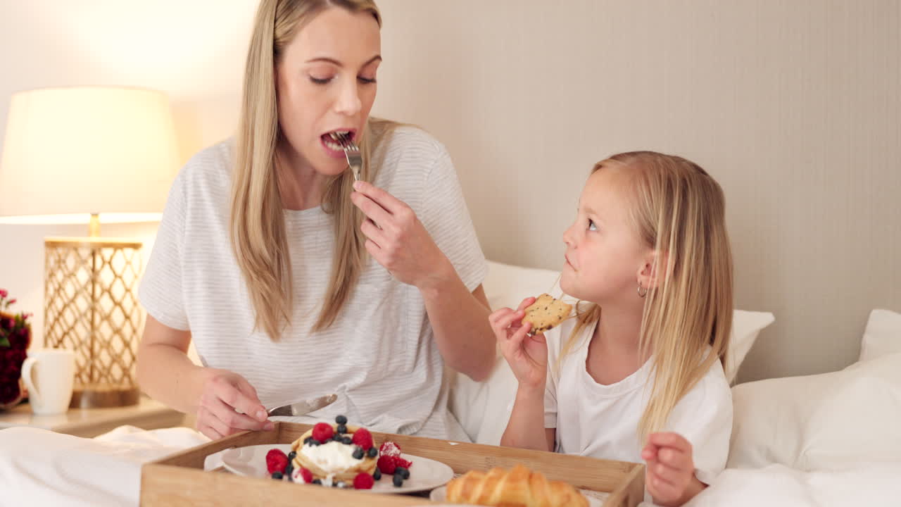 madre e hija disfrutando del desayuno en la cama