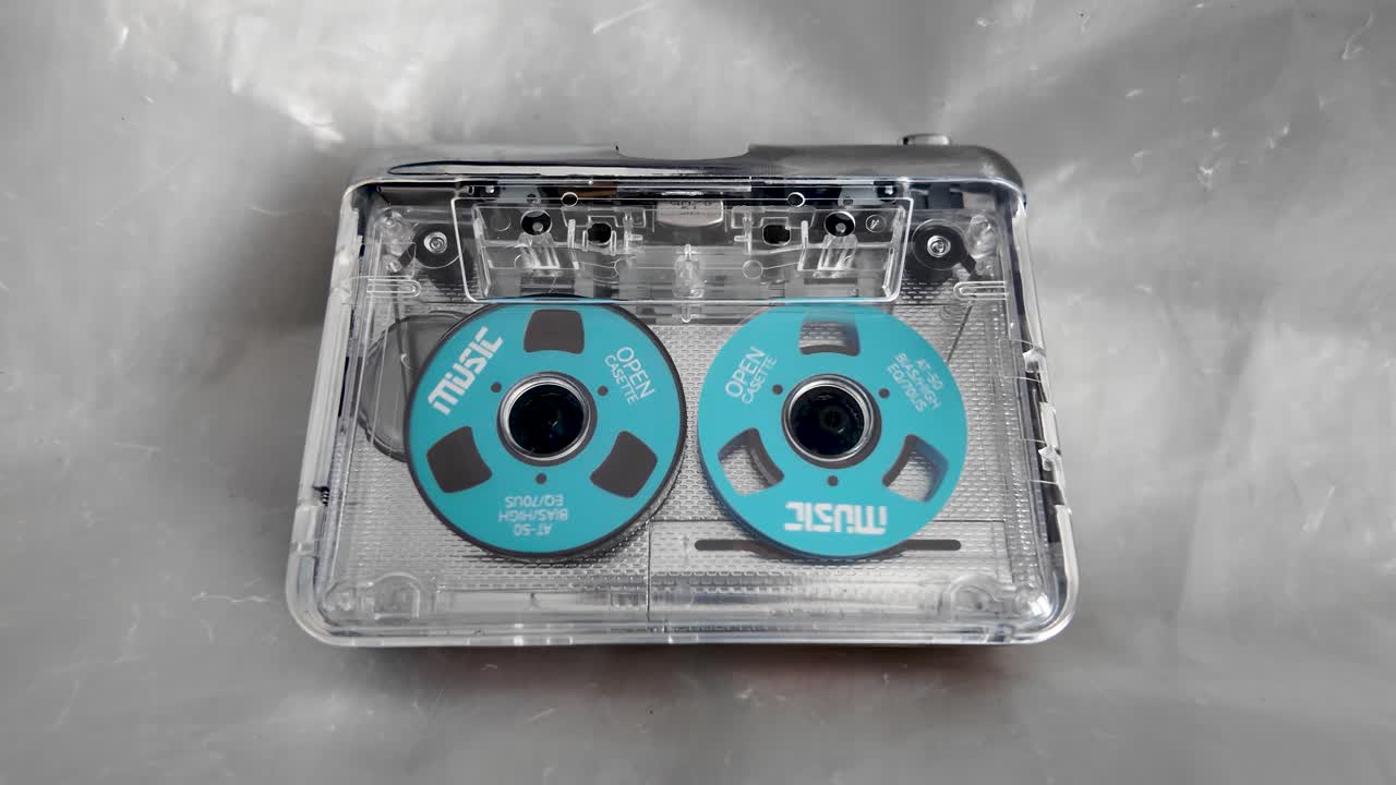 Lettore di cassette portatile retrò trasparente con bobine blu su sfondo grigio.