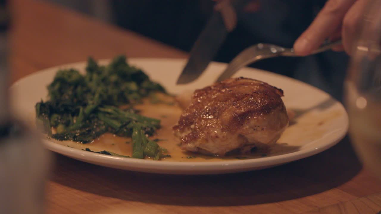 primer plano de un restaurante cortando un pollo asado en su plato con su tenedor y cuchillo
