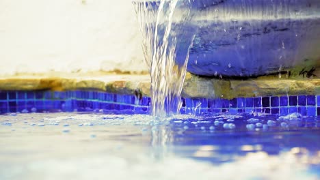 slowmotio disparó agua en cascada en la piscina iluminada por el sol