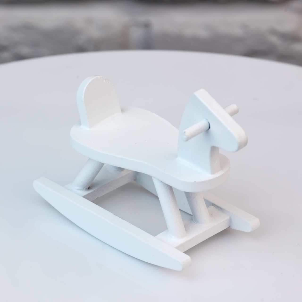 Wooden rocking horse rotating at the table. Small toy decoration for the doll's house interior. White wall background