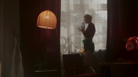 woman using phone by window in vintage home