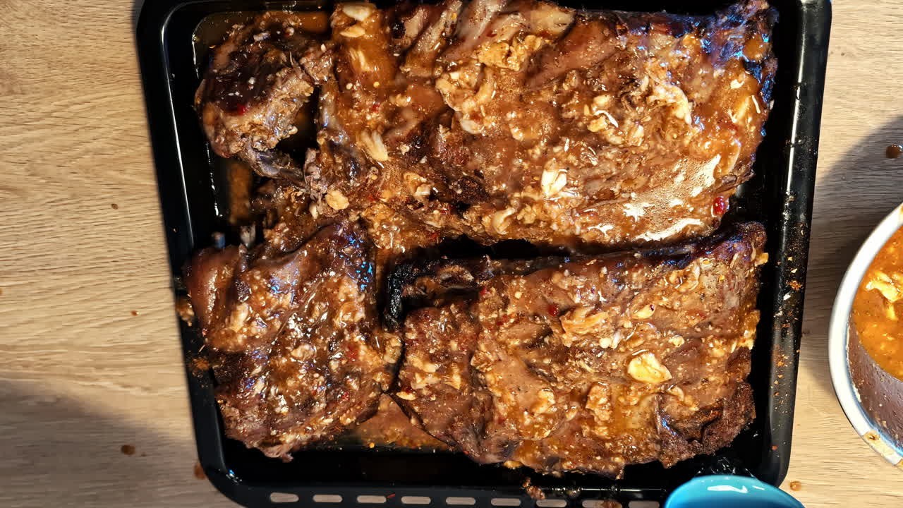 Tray of marinated pork ribs in garlic-spiced sauce on wooden table surface