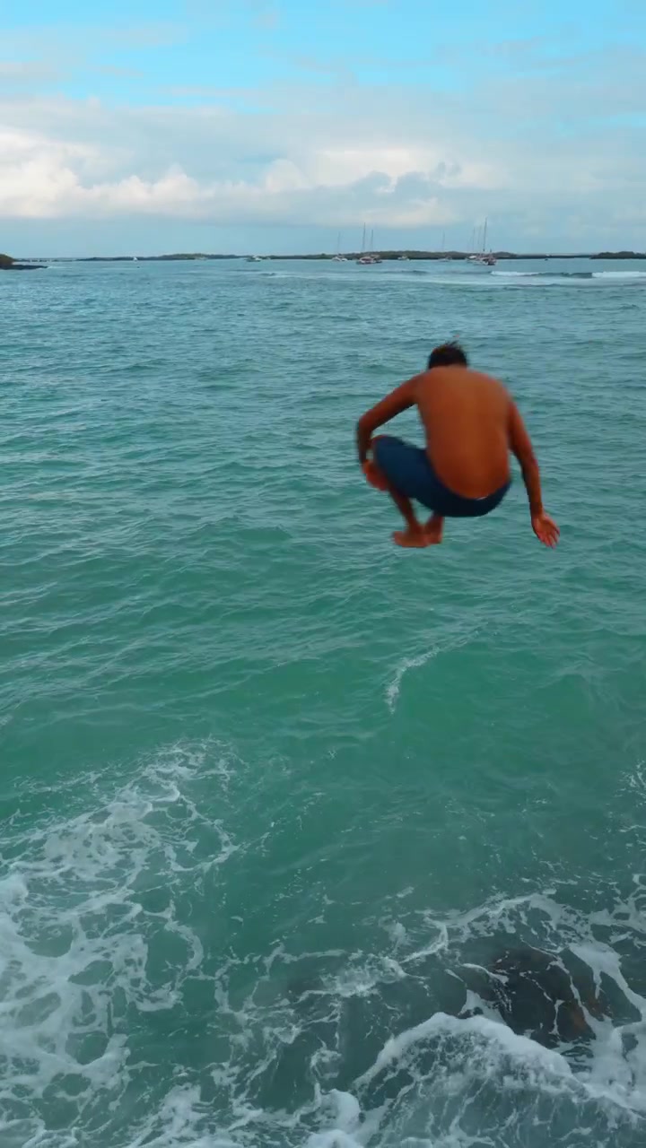 Santo Tomas, Ecuador, 1 maggio 2026: Acqua turchese delle Galapagos con spruzzi e barche ancorate. Acqua di mare turchese con spruzzi, schiuma bianca, barche in lontananza, bassa costa di mangrovie e cielo nuvoloso