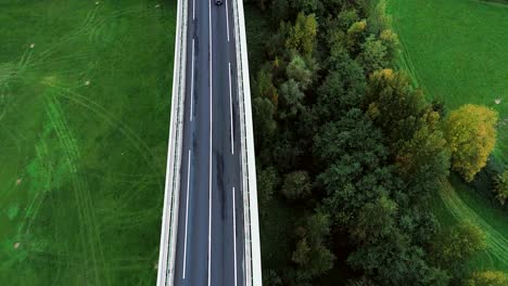 wnderful aerial view over a highway road in france. only grass fields and trees around the roads. cars and trucks driving on the roads under the sun.