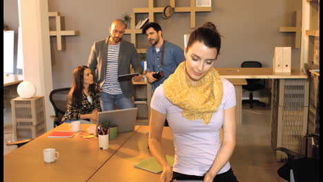 Female-business-executive-using-digital-tablet-while-her-coworker-interacting-in-background