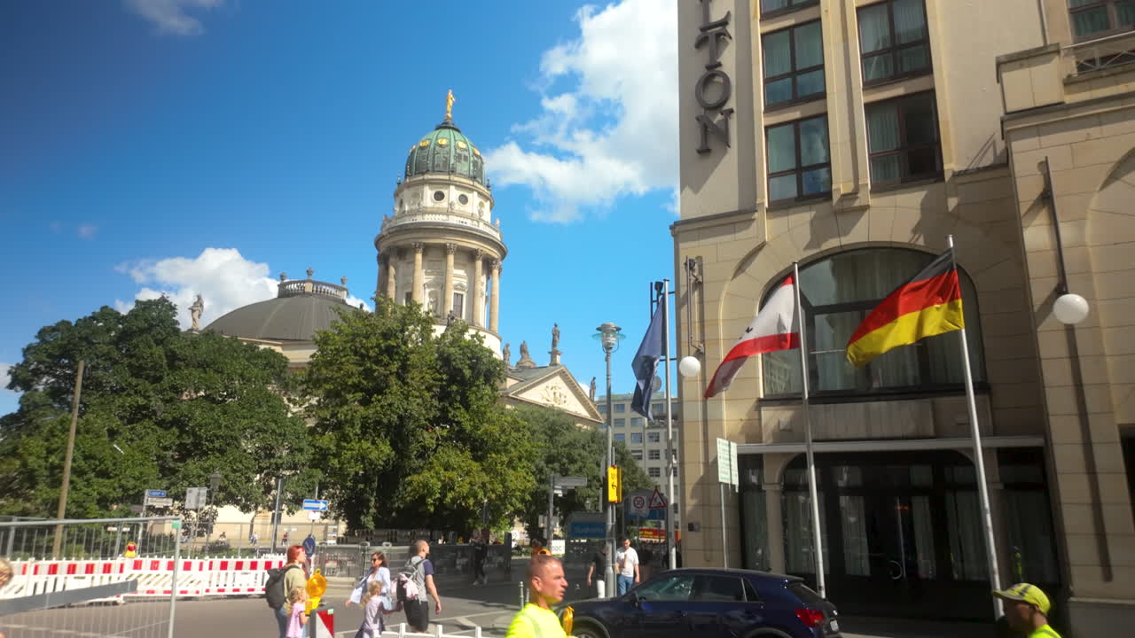 Berlin’s Gendarmenmarkt with cathedral and nearby modern hotel displaying German and Austrian flags