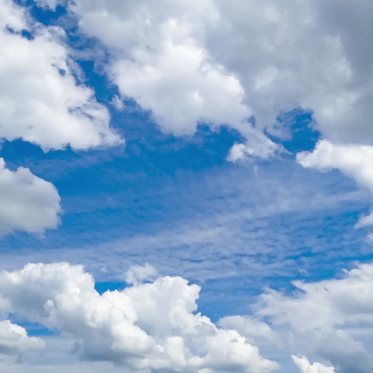 Heavenly beautiful cumulus clouds transforming in the blue skies. Light spindrift clouds at backdrop. Timelapse