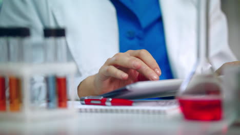 mano de químico usando una tableta pc. mujer química mano de desplazamiento de la tableta computadora