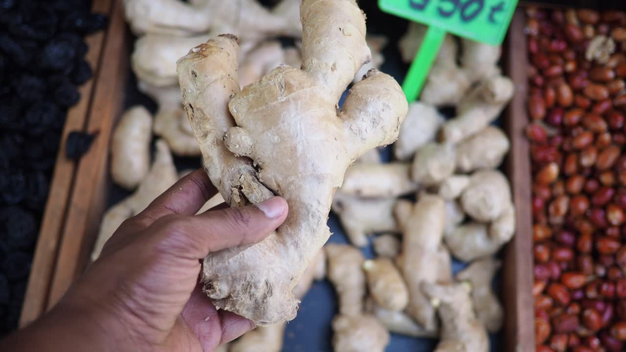 Hand holding fresh ginger at a market