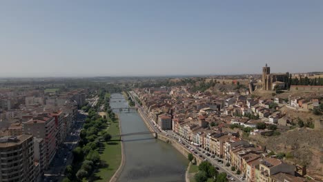 Vuelo-Lento-De-Drones-Sobre-Lleida,-España,-A-Lo-Largo-Del-Río-Segre-En-Un-Día-Cálido