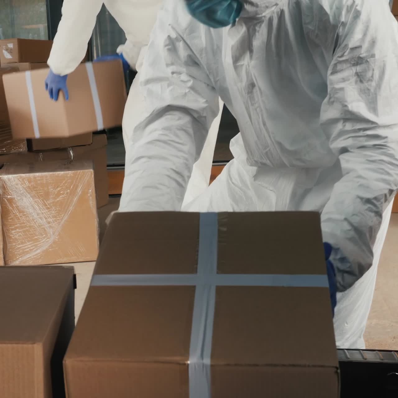 hombres con trajes protectores cargan cajas de medicamentos en el maletero de una furgoneta