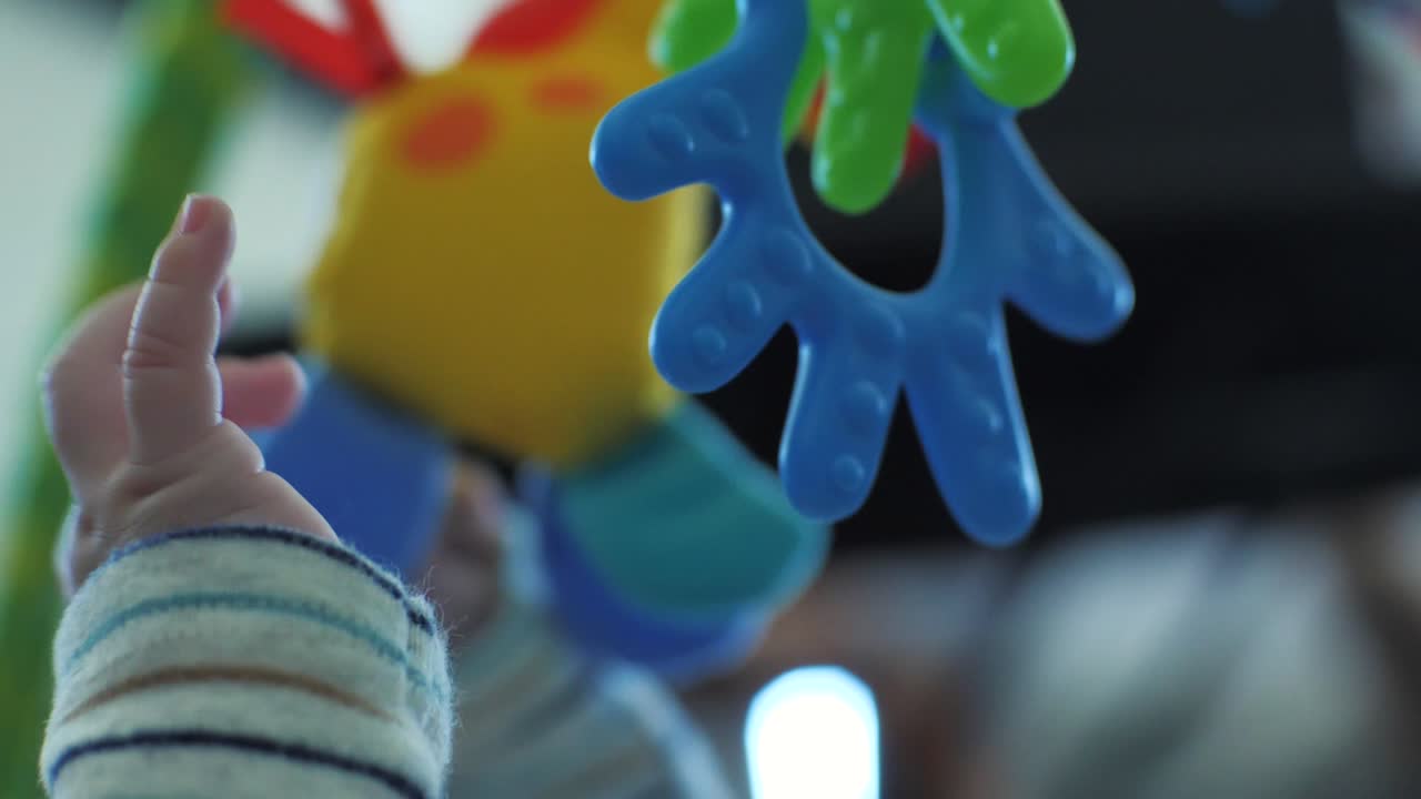 un curioso bebé pequeño alcanza juguetes que cuelgan de un móvil por encima de él