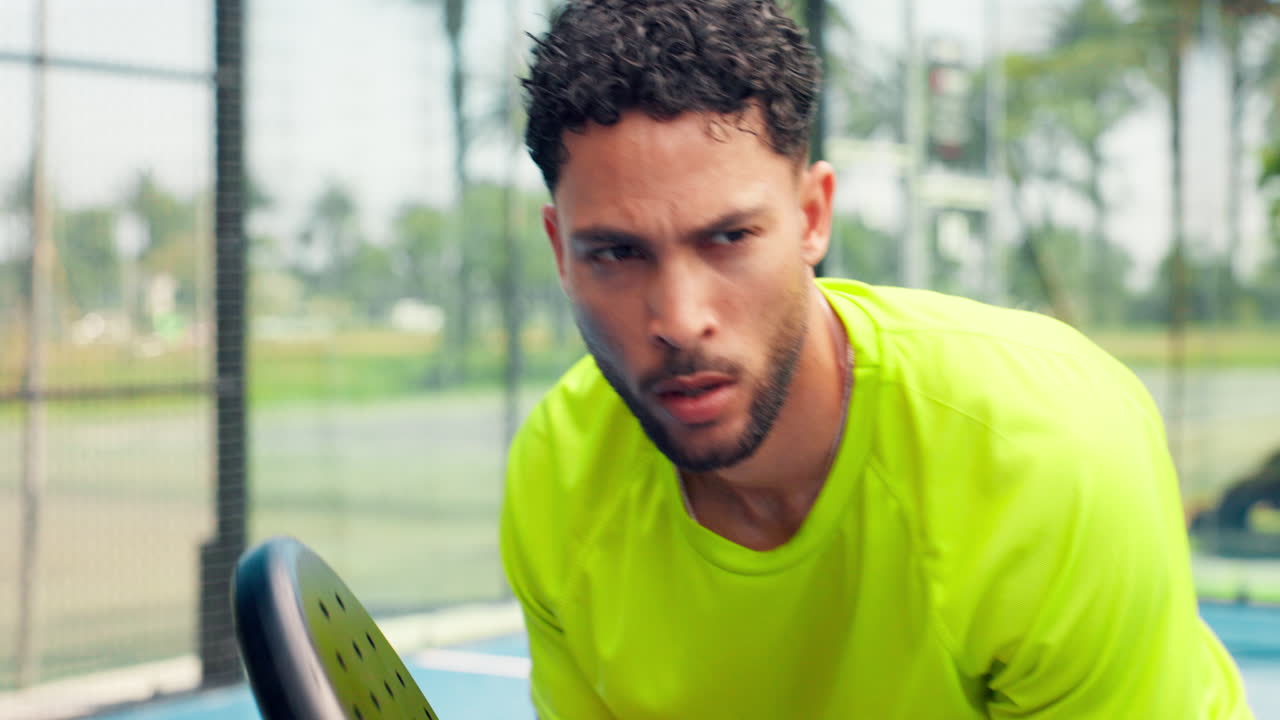 Uomo concentrato che tiene una racchetta da padel su un campo all'aperto