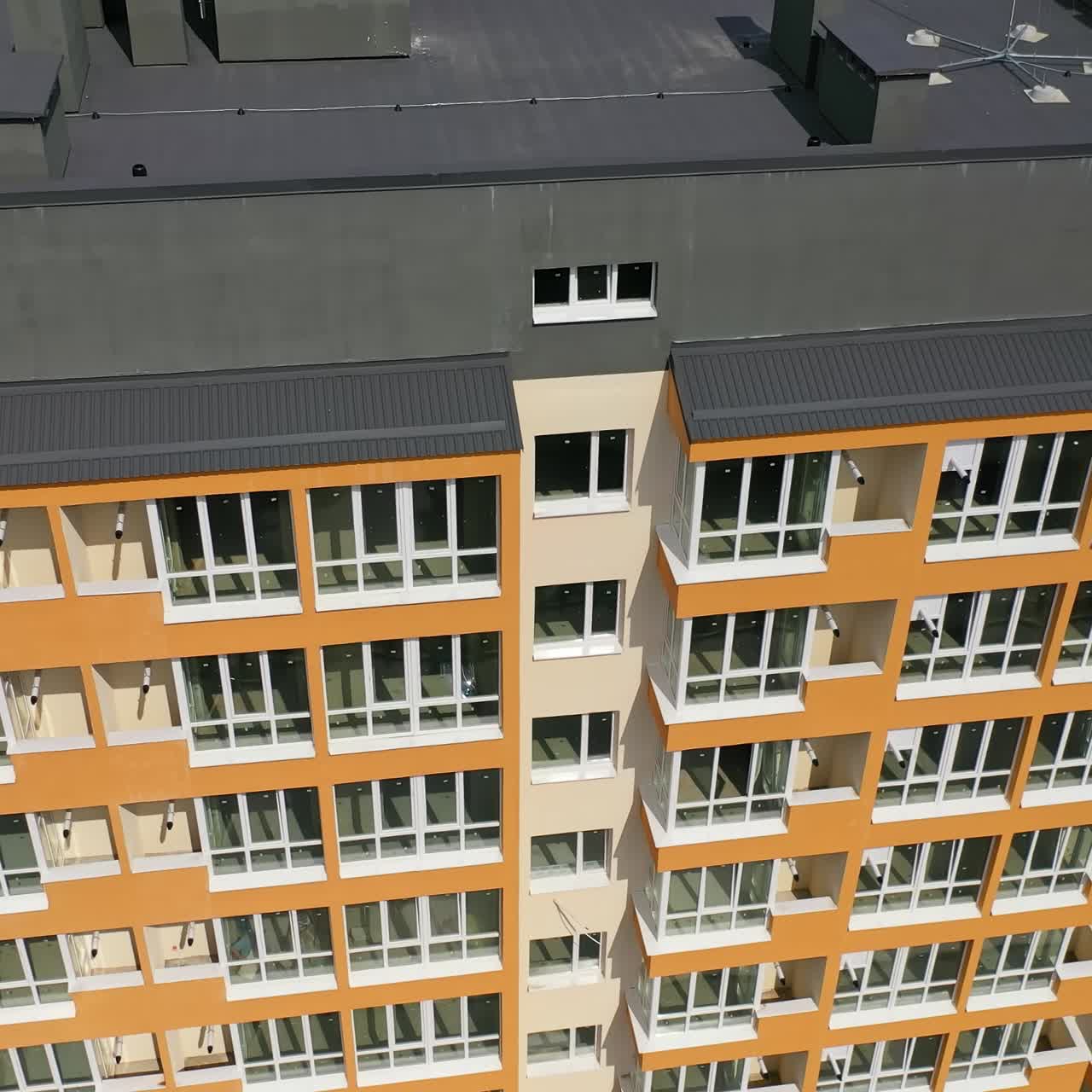 Beautiful design of multistory building. New apartment with balconies against blue sky. Exterior of residential building. Camera rising up. Slow motion