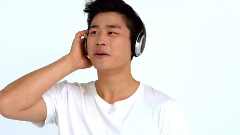 미소 짓는 아시아인 남자가 헤드폰으로 음악을 듣고 있다