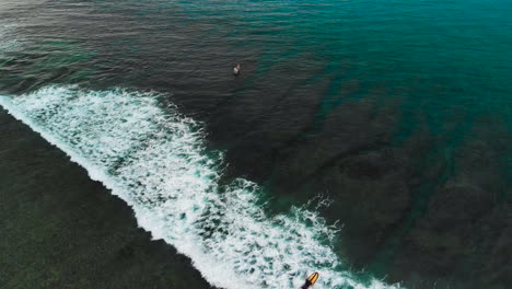 surfer paddling towards the sea, hitting a white wave