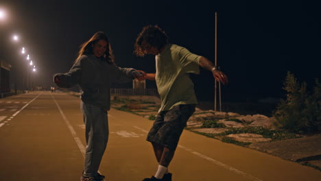 active youngsters training longboard ride at night road. skaters couple kissing