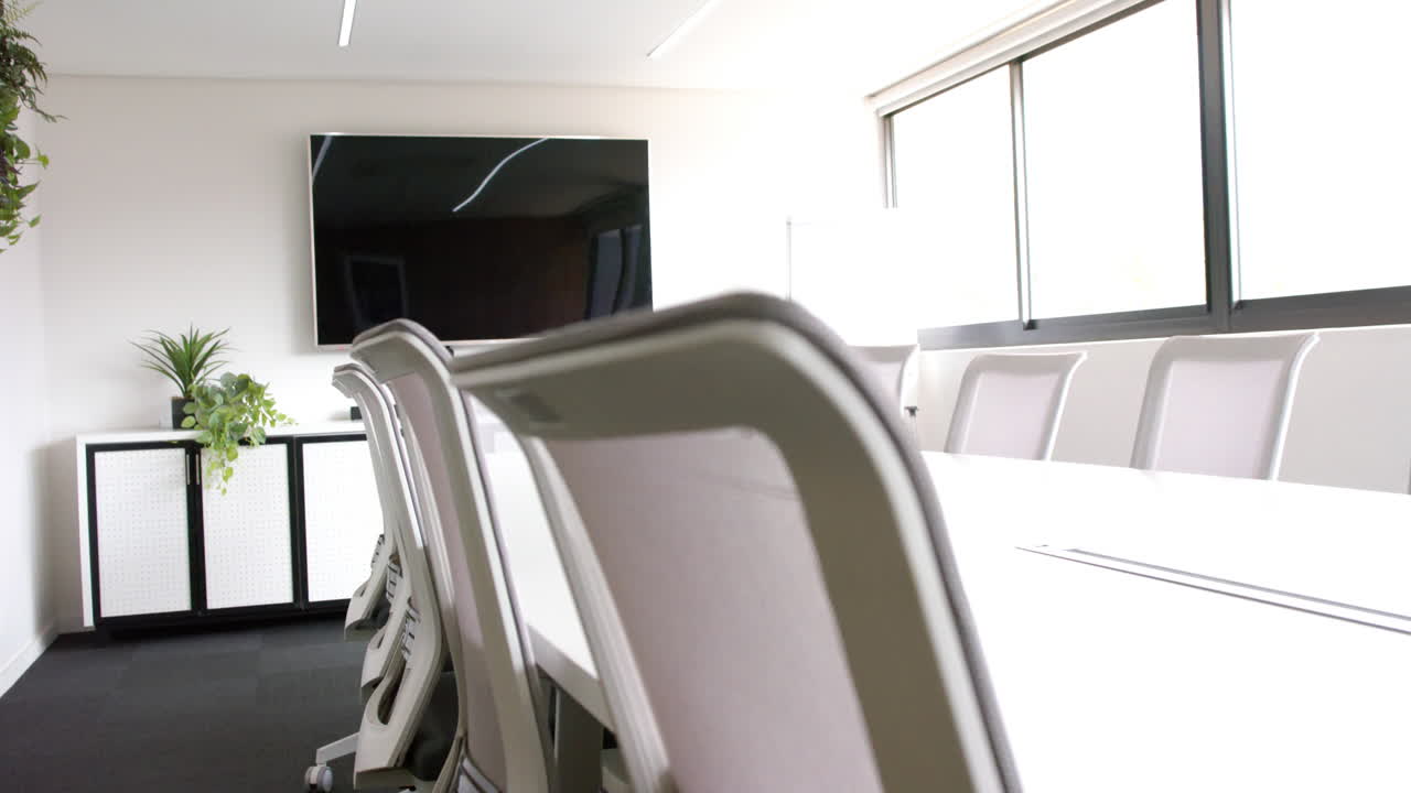 sala de reuniones soleada con mesa, sillas y pantalla en la pared, cámara lenta