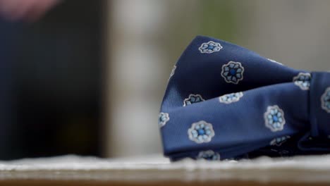 close-up on a fragment of the groom's blue bow tie, with the newlyweds bustling in the background