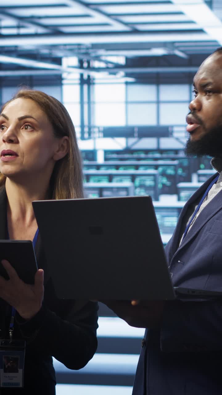 Professionisti IT che discutono in un data center con laptop e tablet