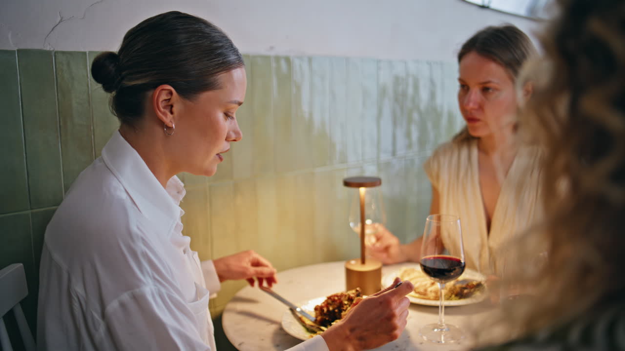 Women group enjoy communication eating dishes in luxury restaurant closeup