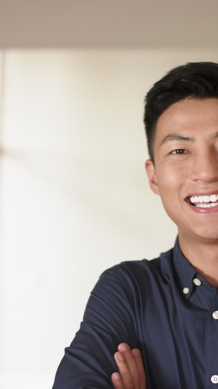 Vertical video of half portrait of happy asian man at home with copy space, slow motion