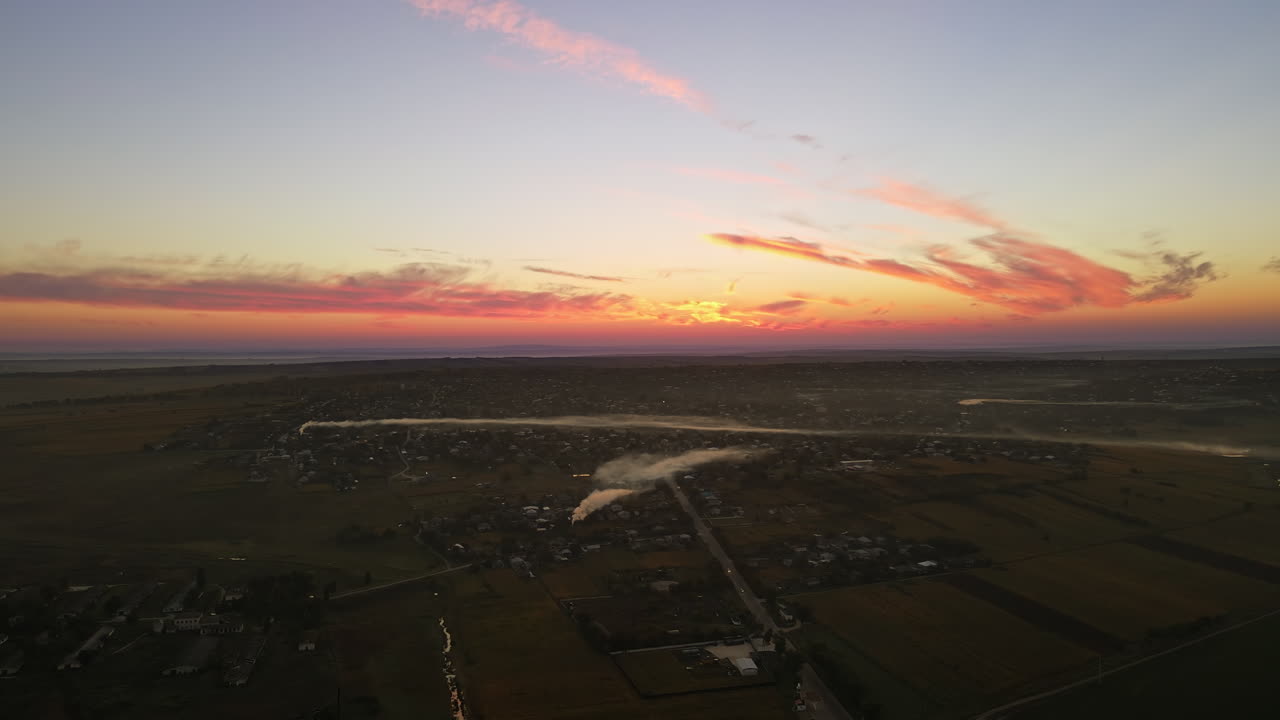 Aerial drone view of village in Moldova at sunset. Few columns of smoke from fires, wide fields