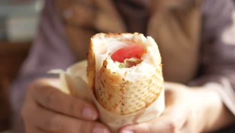 person holding a ham and tomato sandwich