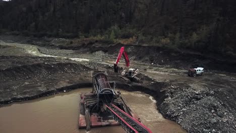 obtenga una perspectiva única de la minería de placer en el yukón: vista aérea de la excavadora que alimenta la tierra productiva en el trommel de la caja de esclusas