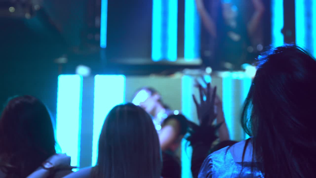 gruppo di persone che ballano in un discoteca al ritmo della musica del dj sul palco