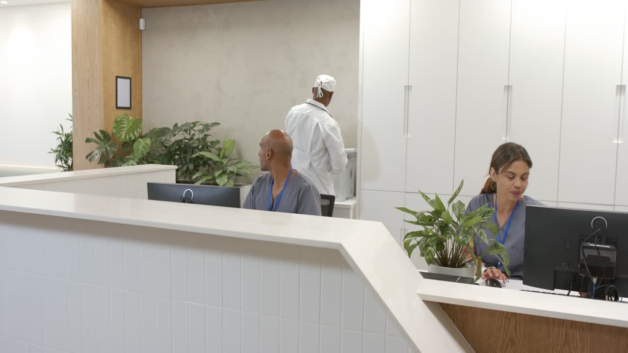 Personale di reception afroamericano, un clinico controlla il monitor mentre si dirige verso la stampante per prendere i rapporti.