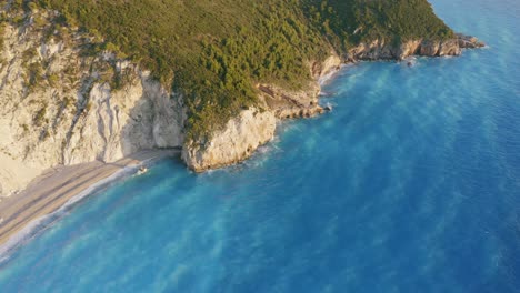 aerial view of beautiful milos beach of lefkada, ionian island, greece. sunset golden sunlight, cliff coastline and pristine waves breaking the turquoise blue sea on the shore