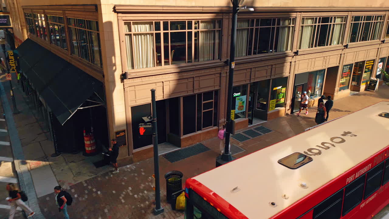 People walk by the sidewalks in a big city. Drone footage above on e of the crossroads in Pittsburg, Pennsylvania, USA