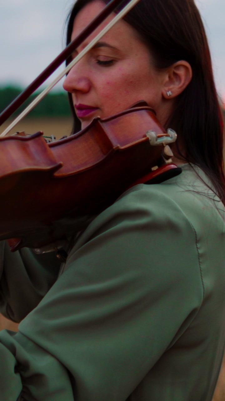 Young Woman Playing Violin in a Field at Sunset