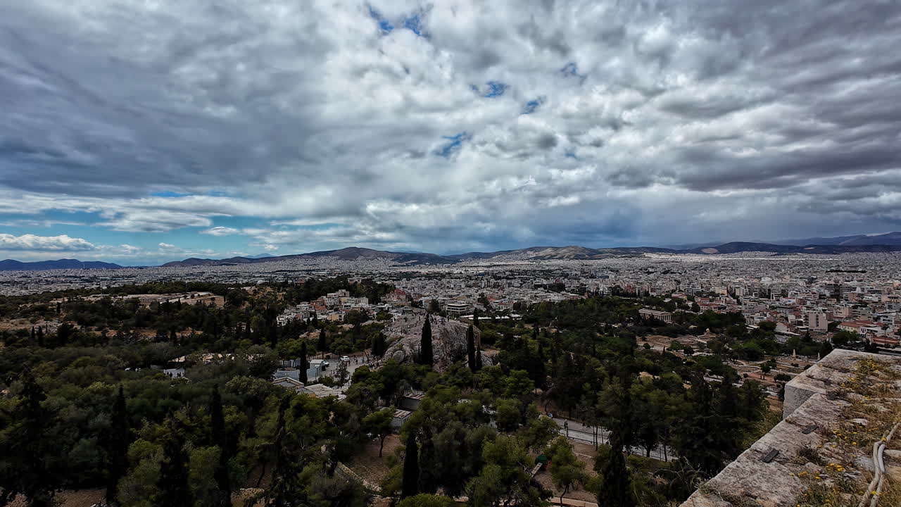Vista panoramica di Atene in una giornata nuvolosa, con punti di riferimento iconici e rovine antiche.
