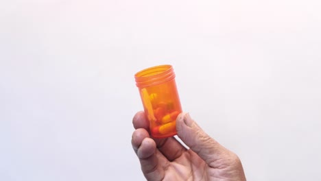 un recipiente de pastillas naranja en la mano