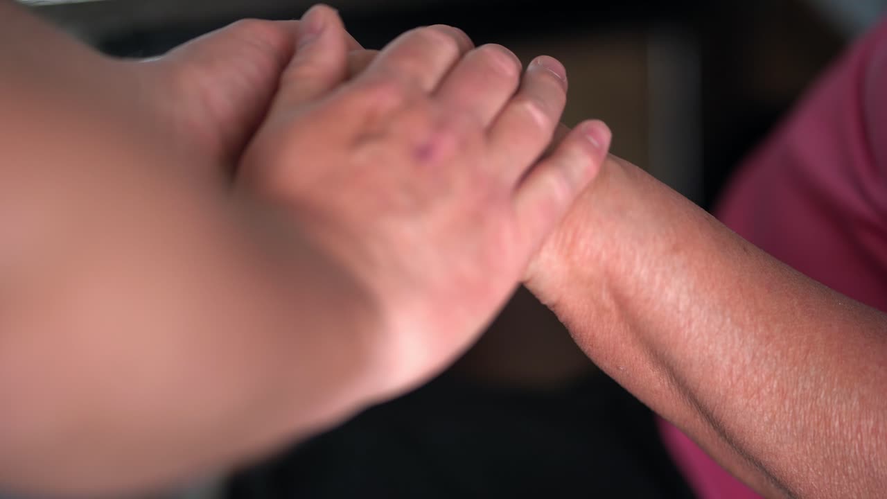 Old woman's hand being comforted by younger male son understanding