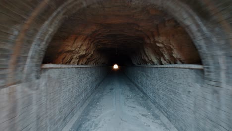 tiré vers l'avant dans un long vieux tunnel en béton, la sortie en bas