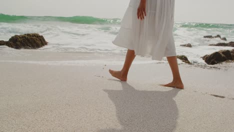 low section of woman walking barefoot on a sunny day at beach 4k