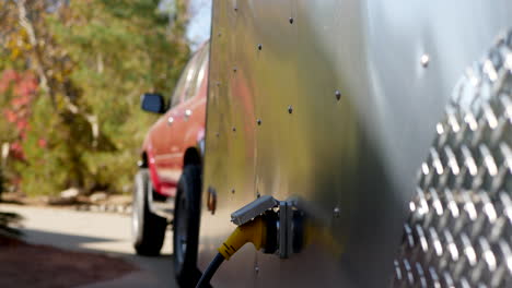 deslizamiento vertical hacia abajo a lo largo del costado de un remolque de viaje de lágrima de metal y vehículo de remolque suv con un enchufe de conexión eléctrica en un sitio de campamento