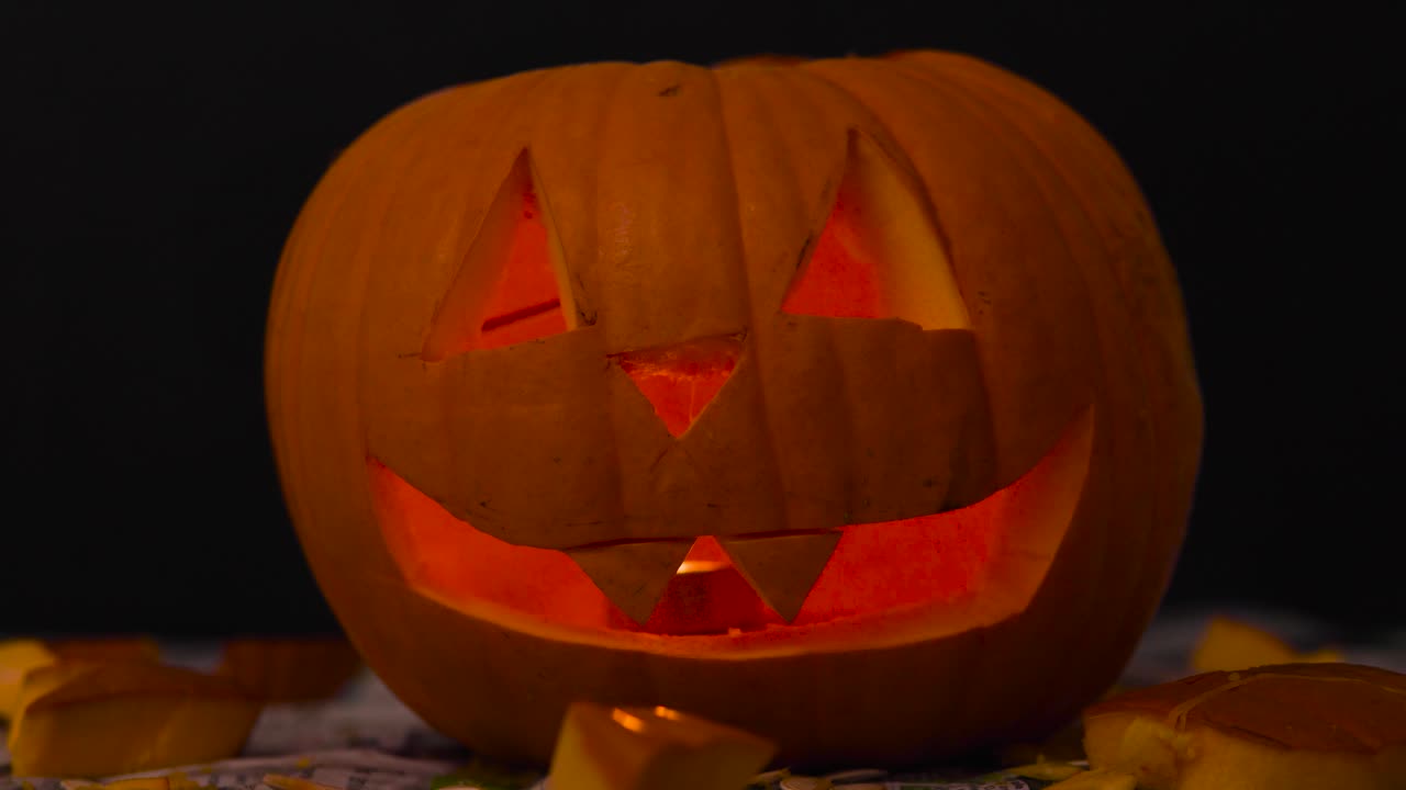 Happy Halloween Creepy Jack O' Lanterns glowing in the dark wishing Happy Halloween: carved Pumpkin decorations with burning candles inside.