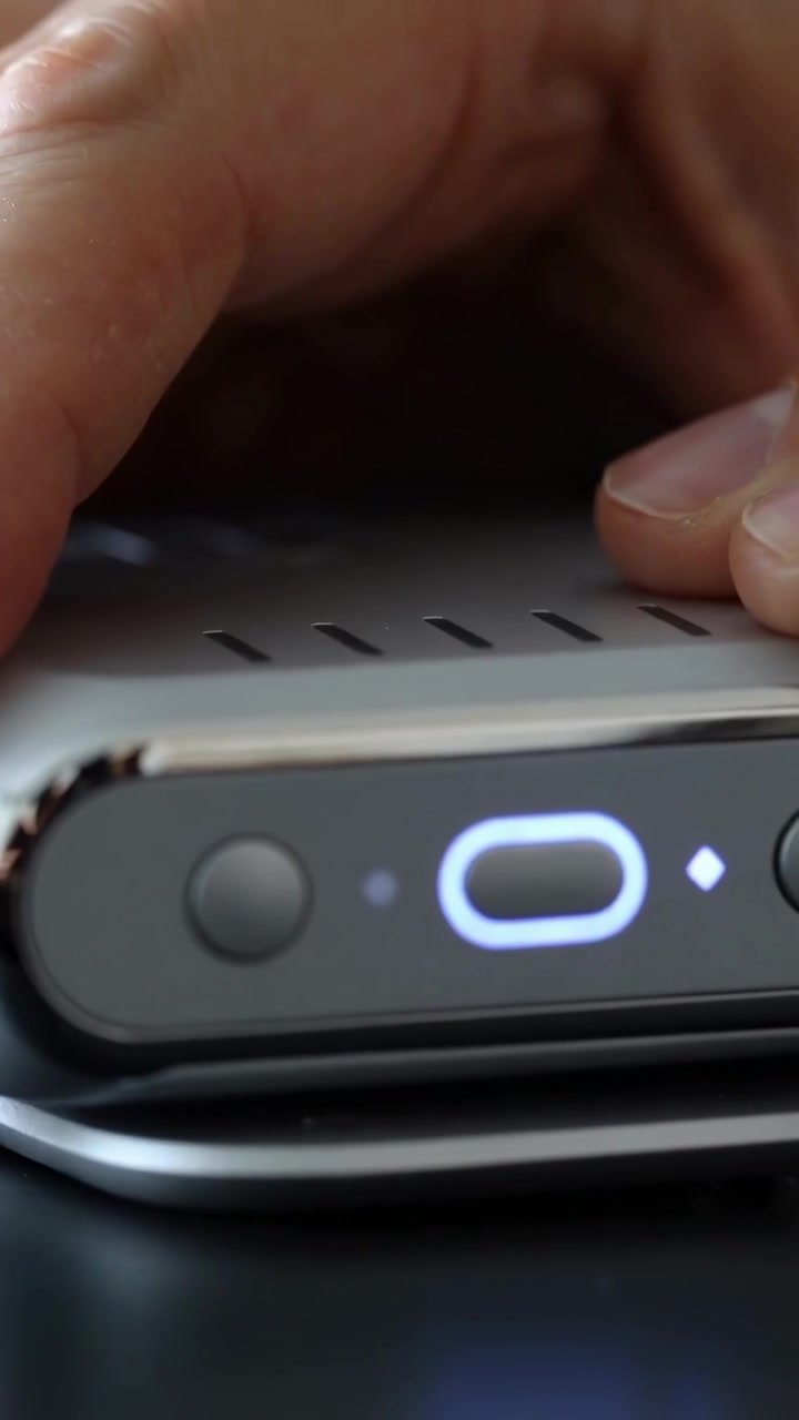 Video verticale: Mano che posiziona un dispositivo a contatto con un pad di ricarica, allineando un LED ovale illuminato per la ricarica.