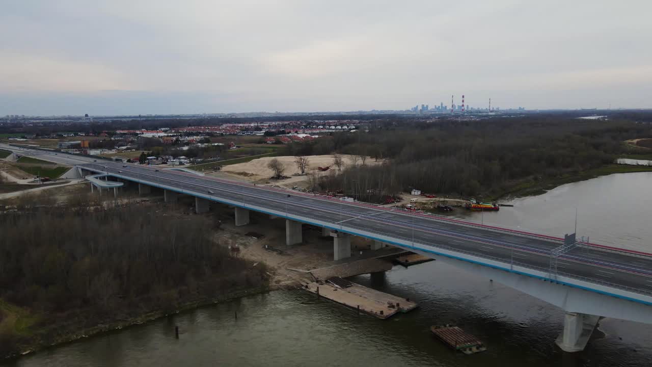 항공: 자동차가 운전하는 현대적인 다리가 비스라 강을 가로질러 건설되고 폴란드의 수도 바르샤바가 배경입니다.
