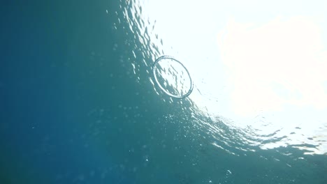 selfie video of a man in mask making bubble ring underwater.