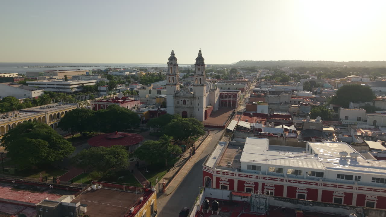 Aerial drone shot flying toward the historic Campeche Cathedral with warm sunrise light in Mexico