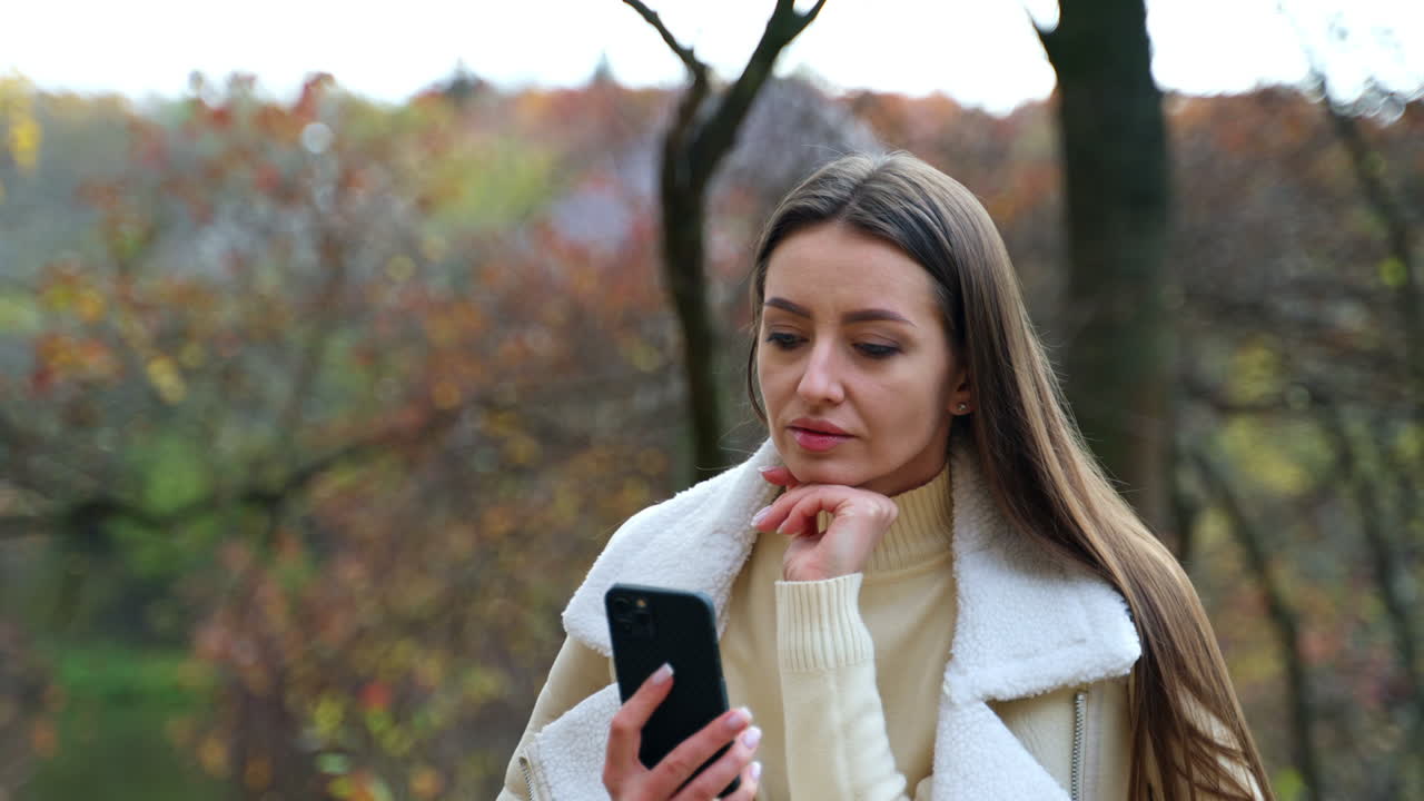 Frau telefoniert im Park im Herbst