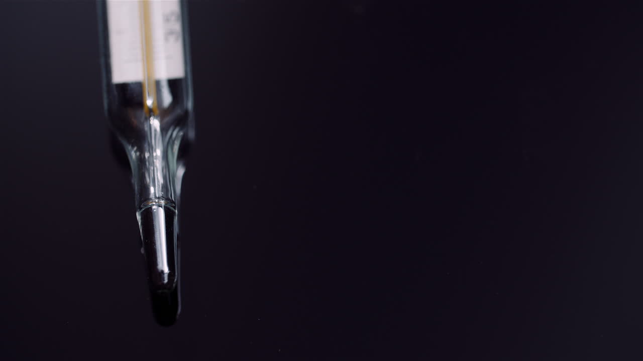 Close-Up of Medical Mercury Thermometer on Black Background