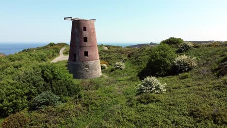 Amlwch-port-red-brick-disused-abandoned-windmill-aerial-view-North-Anglesey-Wales-descending-to-low-shot