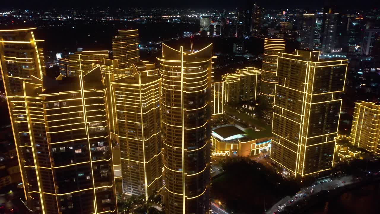 Aerial footage of the Rockwell Center skyscrapers in Makati, Metro Manila, glowing with lights at night and surrounded by the vibrant energy of the city skyline.
